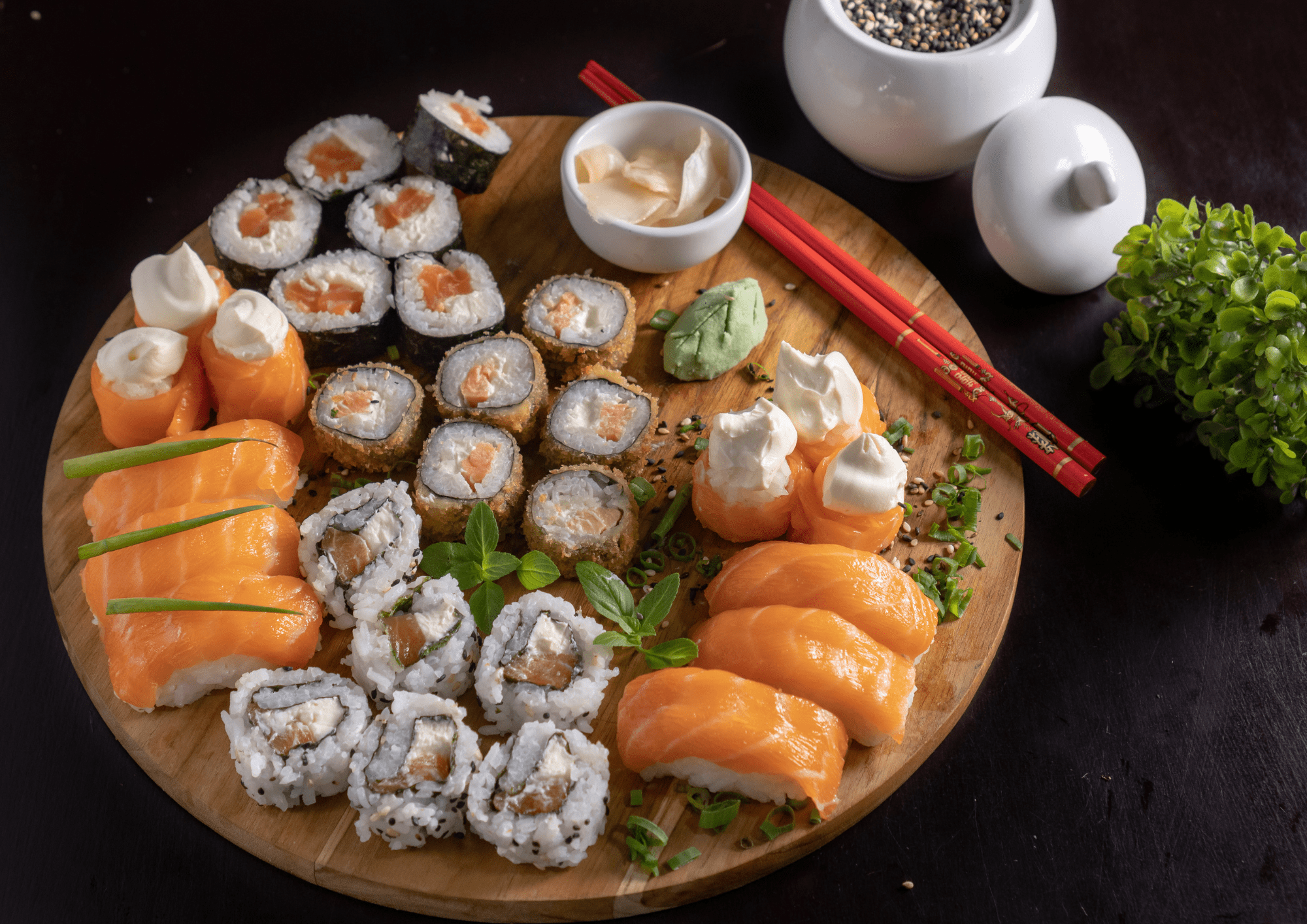 Diferentes sabores de Sushi con salsa y palillos chinos en una mesa de madera redonda